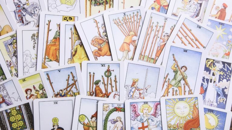 Assorted Tarot cards face up on a surface, displaying Major Arcana figures and colorful wand symbols.