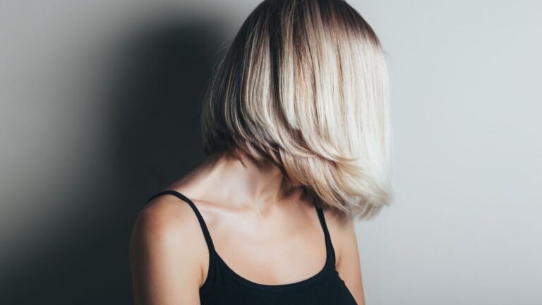 Person with shoulder-length blonde hair turned away from the camera, wearing a black tank top.